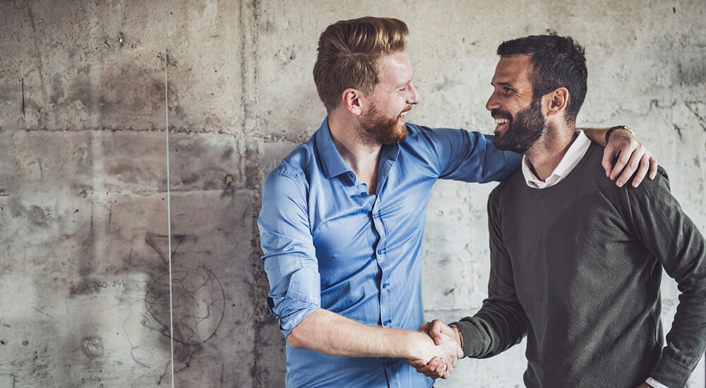 Happy businessmen greeting each other in the office